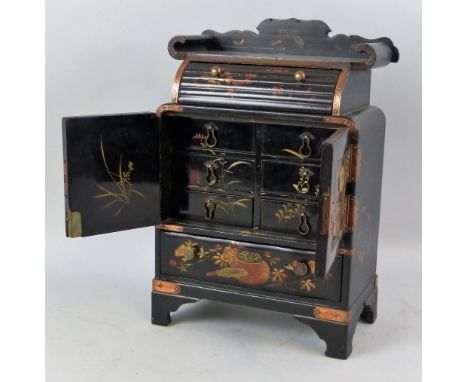 A Japanese black lacquered table cabinet, with chased copper hinges and mounts, the oblong top with shaped back and upward sc