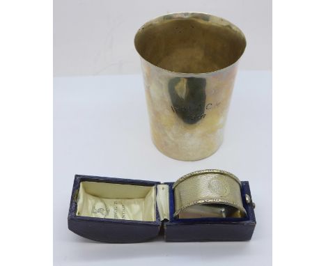 A silver beaker, with inscription dated 1907, and a silver napkin ring, boxed, 131g, (beaker dented) 