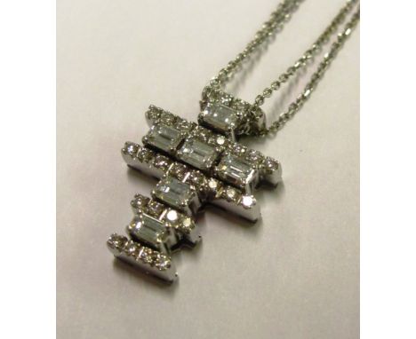 A white gold cross pendant set with 28 brilliant cut and six emerald cut diamonds on a white metal double chain necklace