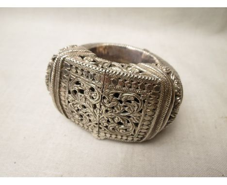 A Far Eastern white metal slave bangle of heavy gauge with pierced and scrolled leaf decoration, total weight 262.6g
