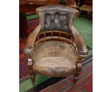 An early Victorian oak desk chair, leather scrolling button back, padded curved and spindled arm rail, stuffed overseat, reed