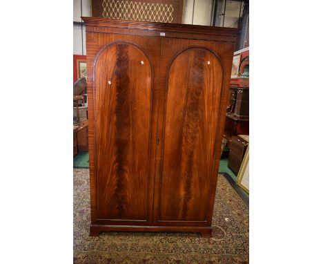 A reproduction flame mahogany double wardrobe, ogee cornice, two arched panel doors, spreading bracket feet, 201cm high x 129