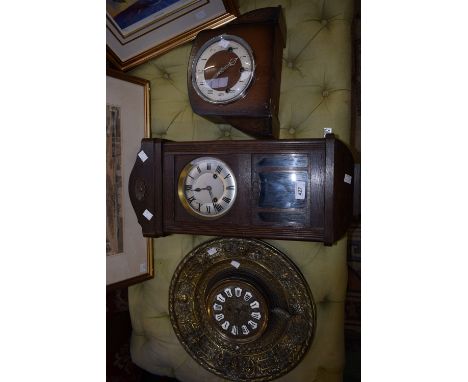 An early 20th century neo classical circular brass wall clock inset with enamel Roman numerals; an oak wall clock; another, m