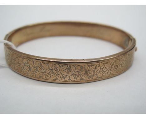 A Bangle, leaf engraved to the front, hinged to snap clasp, inscribed "From Lila in Memory of Granny". 