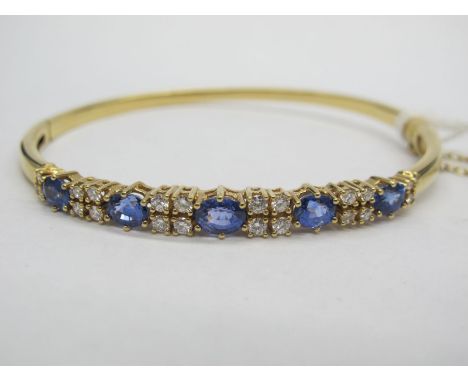 A Modern 18ct Gold Diamond Set Bangle, alternately claw set to the front, hinged to snap clasp.