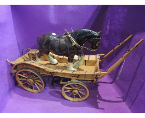 A hand made wooden four wheel cart being pulled by a ceramic shire horse with harness
