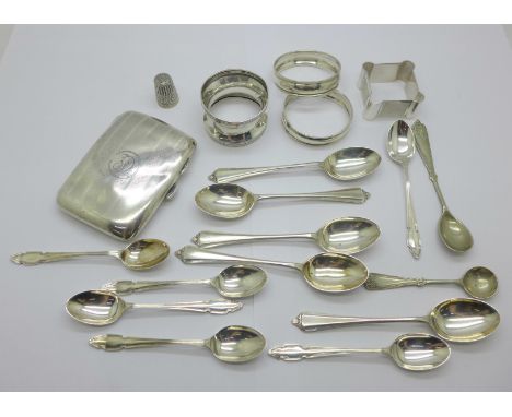 A silver cigarette case, four silver napkin rings, eleven silver spoons, two plated spoons and a silver thimble, silver weigh