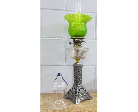 An oil lamp with green glass shade and a glass bell dome