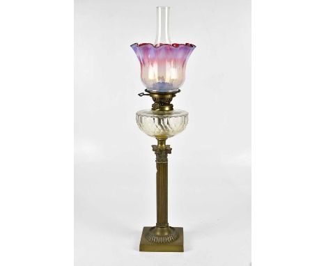 A Victorian brass Corinthian column oil lamp with vaseline and cranberry glass shade above the Hinks patent cut glass reservo