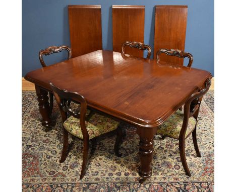 A reproduction mahogany pull out extending dining table, on turned column supports with three additional leaves, and five Vic