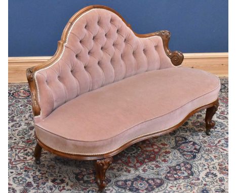 A Victorian carved walnut button back upholstered settee in pink material, on front scrolling legs.