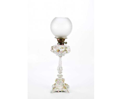 An early 20th century Continental porcelain oil lamp with frosted glass shade above the ceramic reservoir and column, with fl