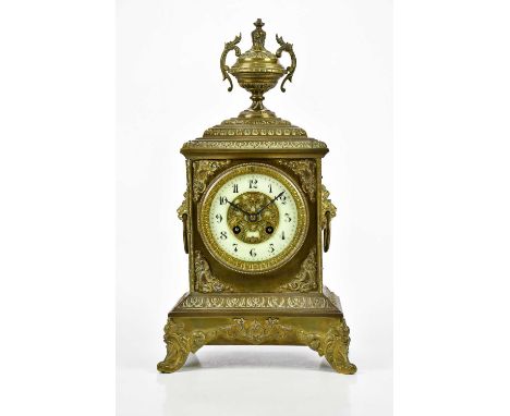 A late 19th century French brass cased mantel clock, with twin handled urn finial above the dial set with Arabic numerals, wi