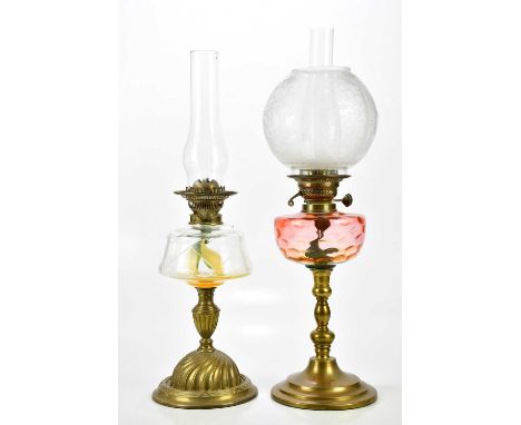 An early 20th century oil lamp, the etched glass shade with floral decoration, with cranberry glass reservoir, on brass base,