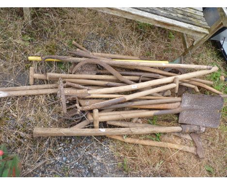 A large quantity of garden tools to include: spades, a pitch fork, etc.