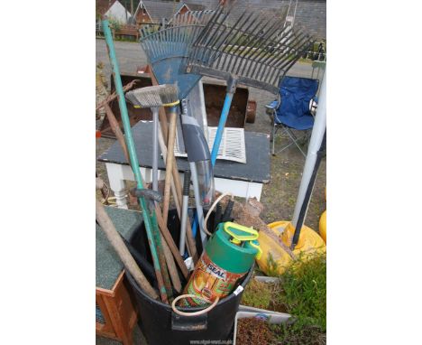 A tub of garden tools, pick axe, valves, sprayer, forks, etc.