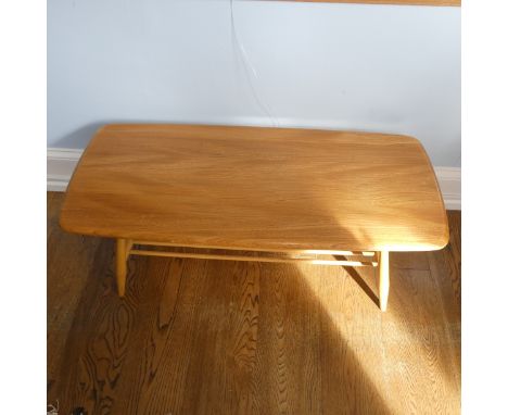 An Ercol blonde Elm and Beech 'Windsor' Coffee Table, of rounded rectangular form, with spindle rack undertier to the splayed