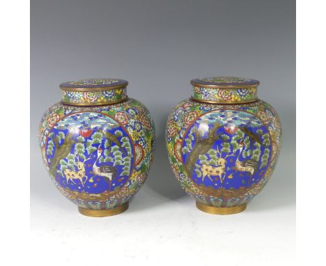 A pair of Japanese cloisonne lidded Jars, decorated with a panel depicting birds and mythical beasts in a landscape, enclosed