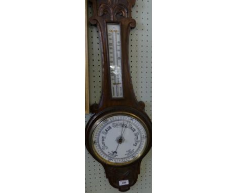 A late 19th Century oak cased aneroid barometer and thermometer combination with carved detail. 