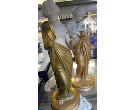 A pair of Royal Worcester figurines each depicting semi-nude shy ladies with gilt dresses and highlights, each with puce fact