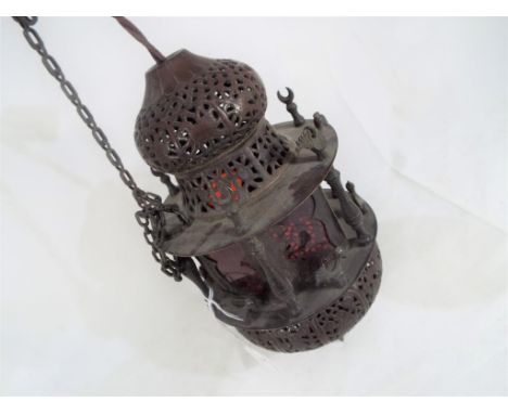 A good quality Moroccan style lantern with chains, pierced decoration and red glass panels, height excluding chains 30cm This