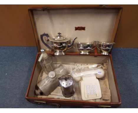 A vintage leather suitcase containing a miner's safety lamp, a vintage telephone handset, plated cruets, a foot warmer and a 