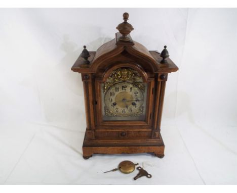 An early 20th century beech cased bracket style clock, silvered arched dial with cast spandrels and applied decorative dial, 