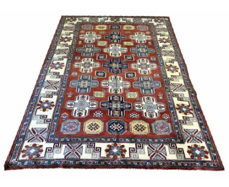 KAZAK CARPET, 241cm x 167cm, geometric medallions on a ruby field within corresponding borders.