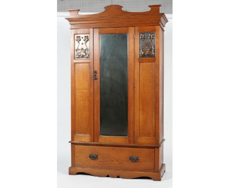 An Art Nouveau oak wardrobe, inset with two foliate copper panels flanking a central mirror, the interior with rail, with low