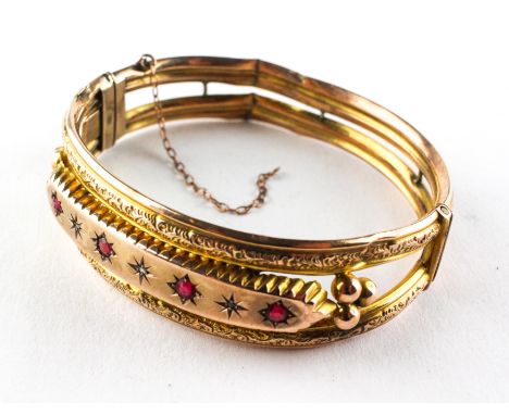 A yellow metal bangle set with synthetic rubies and rose cut diamonds. Push in clasp with fitted safety chain. Stamped 9ct. 1