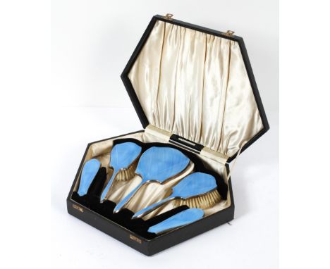 An Art Deco silver-mounted blue guilloche enamel dressing table set, comprising: four brushes and a mirror, in fitted leather