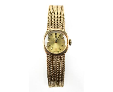 A yellow gold omega wristwatch. Circular gold dial with baton markings. Integrated 9ct gold weave bracelet. Clip and ladder c
