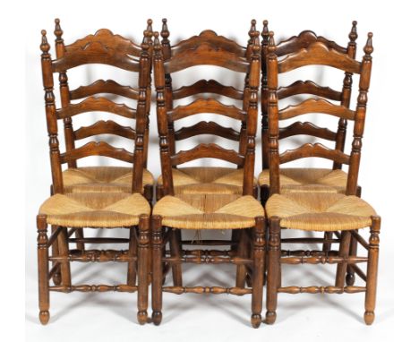 A set of six oak ladder back dining chairs with rush seats, with turned finials, baluster uprights and stretchers, 113 cm hig
