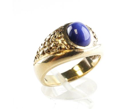 A yellow metal ring set with an oval cabochon synthetic star sapphire. No hallmark - stamped 10K. Size Q 7.9 grams