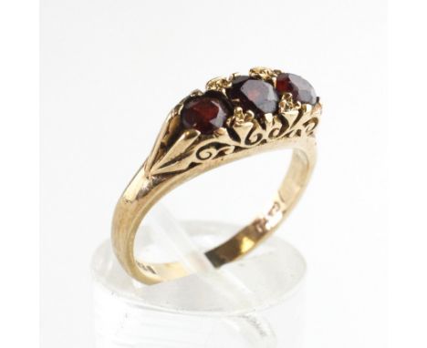 A yellow metal carved half hoop ring set with three round cut garnets. Hallmarked 9ct gold, London, 1974. Size: I ½ 3.2 grams