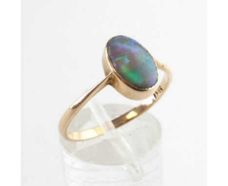 A yellow metal ring set with an oval cabochon cut black opal. No hallmark - shank stamped 15C Size R 2.2 grams