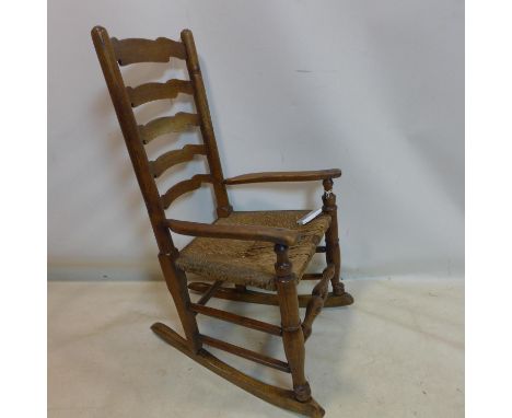 A 19th century oak ladder back rocking chair with original rush seat 