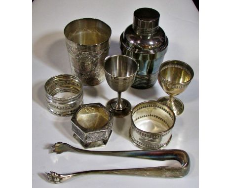 A silver French beaker, bearing the head of Minerva, two napkin rings, a clawed sugar tong, three assorted silver metal egg c