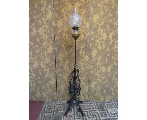 A late Victorian telescopic oil lamp standard with good quality scrolled wrought iron base beneath a glass font with duplex b