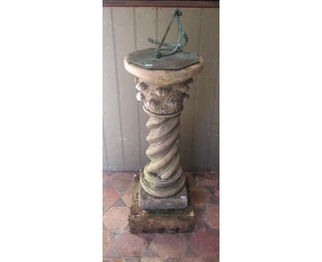 A  two sectional weathered cast composition stone garden sundial, the octagonal verdigris dial set on a spiral column and squ