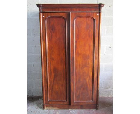 A substantial Victorian mahogany wardrobe with turret corners enclosed by a pair of arched and panelled doors, 130cm wide x 2