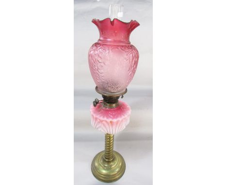 An antique brass column oil lamp with faded pink font and pink etched glass shade, 82cm high approx. 