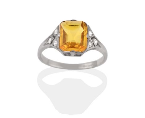 A Yellow Sapphire and Diamond Ring, in the Art Deco Style, the emerald-cut yellow sapphire in white claws sits between pierce