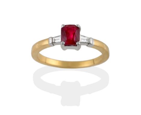 An 18 Carat Gold Ruby and Diamond Three Stone Ring, the modified emerald-cut ruby sits between two tapered baguette cut diamo