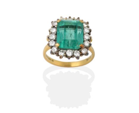 An 18 Carat Gold Emerald and Diamond Cluster Ring, the step-cut emerald in yellow claw settings, within a border of round bri