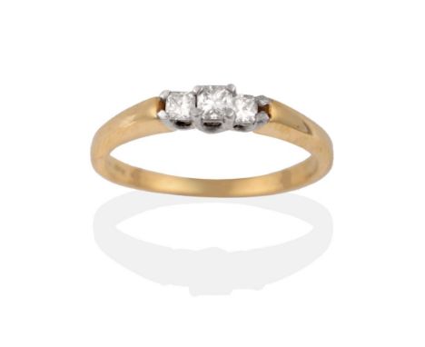 A Diamond Three Stone Ring, the graduated princess cut diamonds in white claw settings, to a yellow tapered shoulder plain po