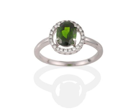 A Green Garnet and Diamond Cluster Ring, the oval cut green garnet within a halo of round brilliant cut diamonds in white cla