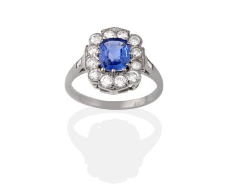 A Sapphire and Diamond Cluster Ring, the cushion cut sapphire within a border of round brilliant cut diamonds with a baguette