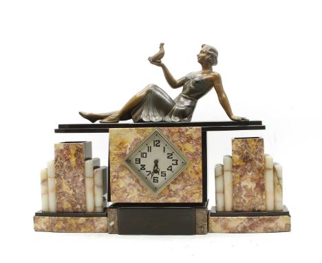 An Art Deco marble and slate mantle clock, surmounted with a girl with a dove, the diamond shaped dial, lacking glass, 48cmCo