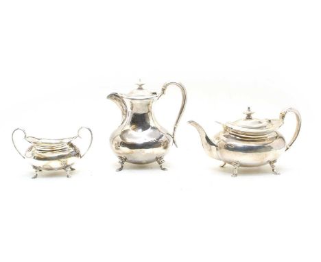 An early 20th century silver three piece tea service, comprising teapot, hot water jug and sucrier, having loop handles and s